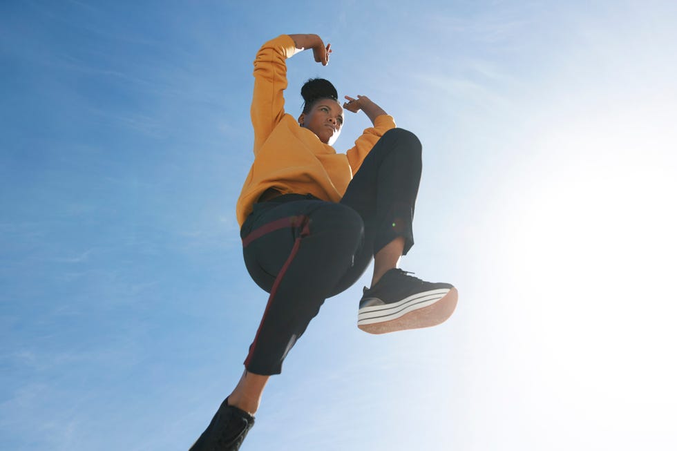 directly below shot of carefree woman jumping against blue sky