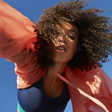 directly below shot of female athlete with curly hair against clear sky