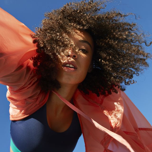 directly below shot of female athlete with curly hair against clear sky