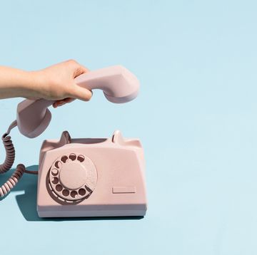 womans hand putting a retro telephone reciver down, hanging up pastel colors blue and pink