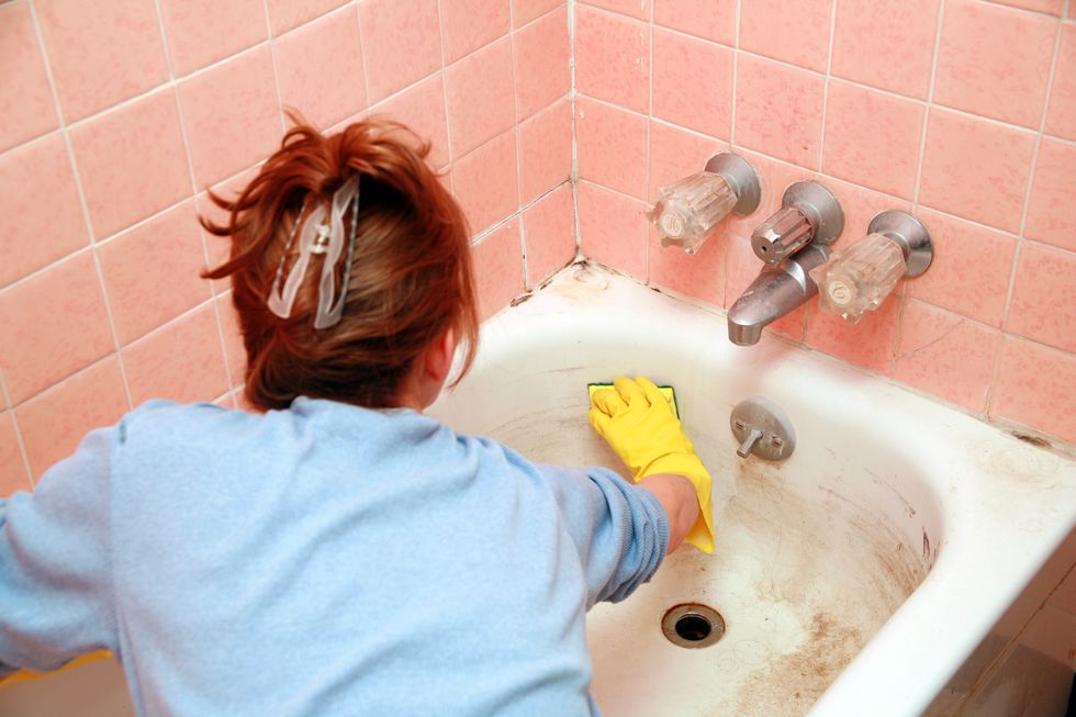 woman cleaning dirty bathtub