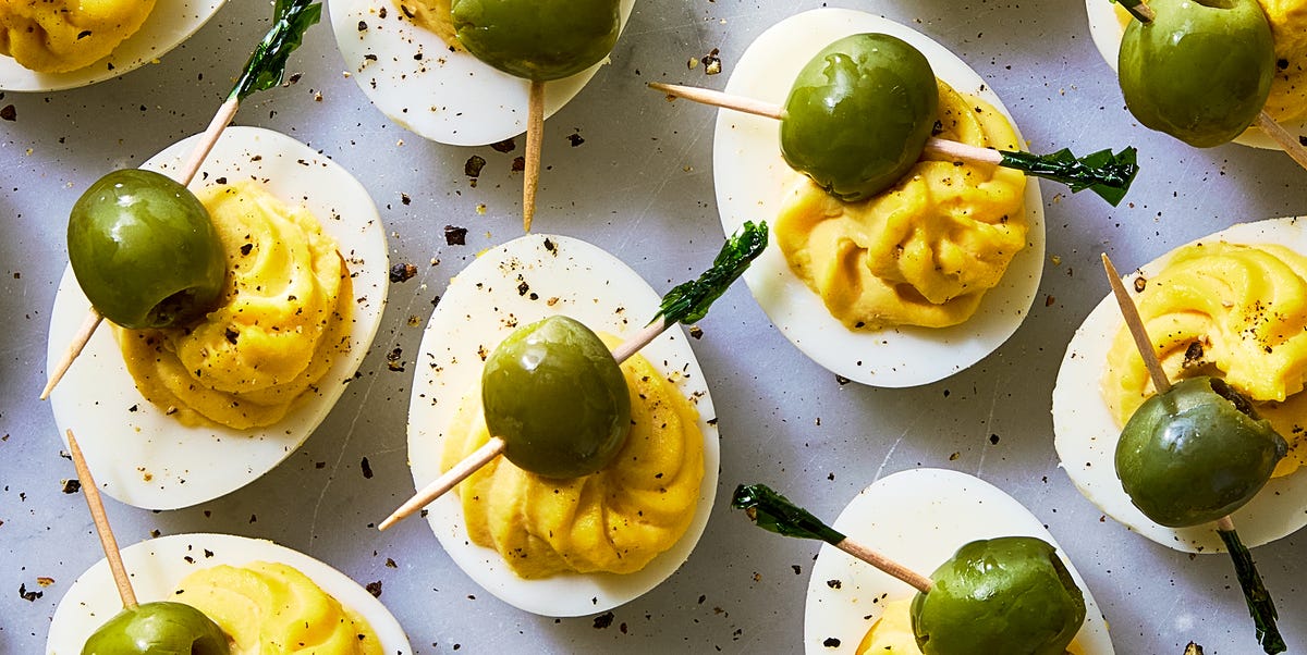 Dirty Martini Deviled Eggs deviled eggs decorated to look like dirty martinis with olives on a toothpick