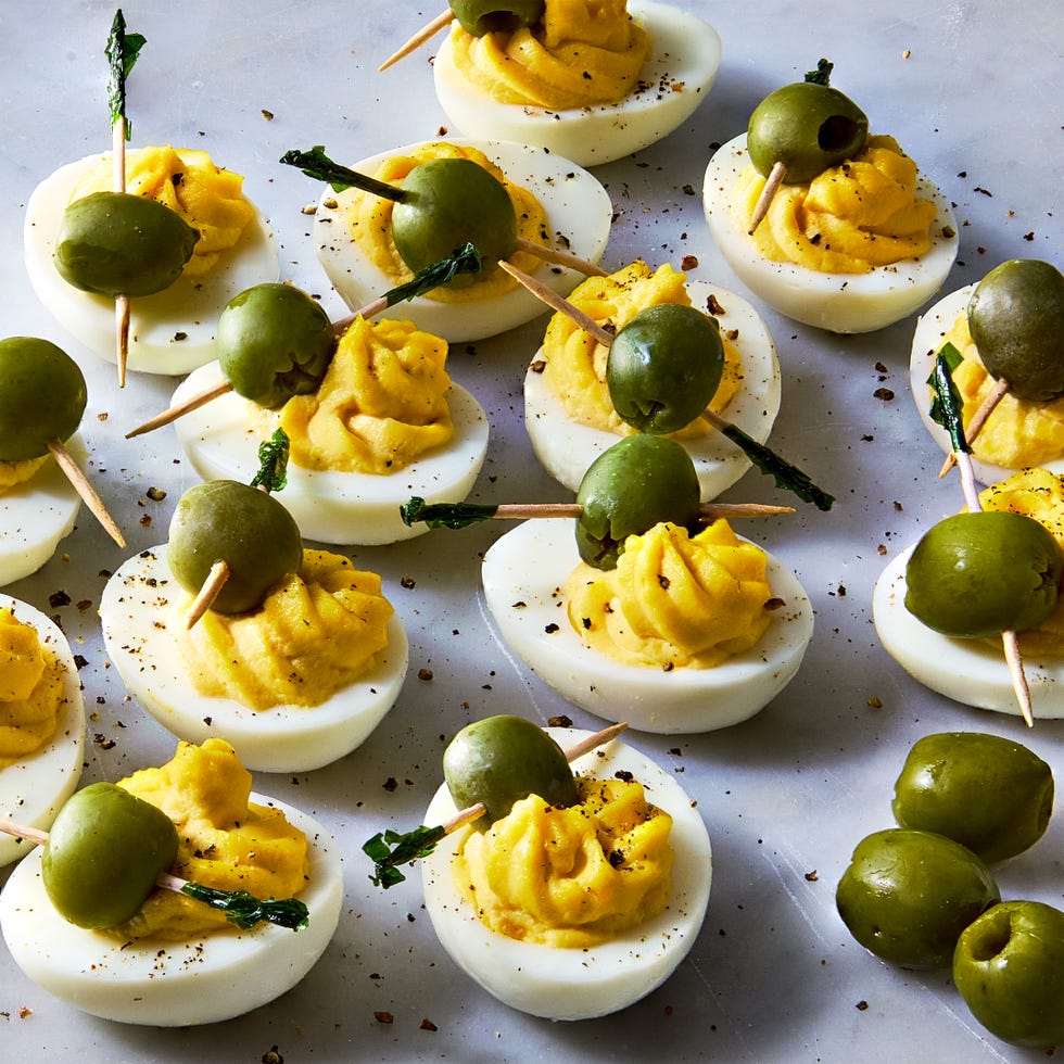 deviled eggs decorated to look like dirty martinis with olives on a toothpick
