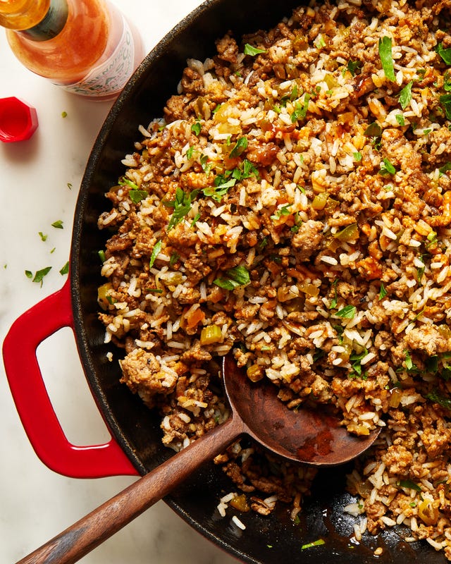 dirty rice topped with chopped parsley in a red cast iron pan