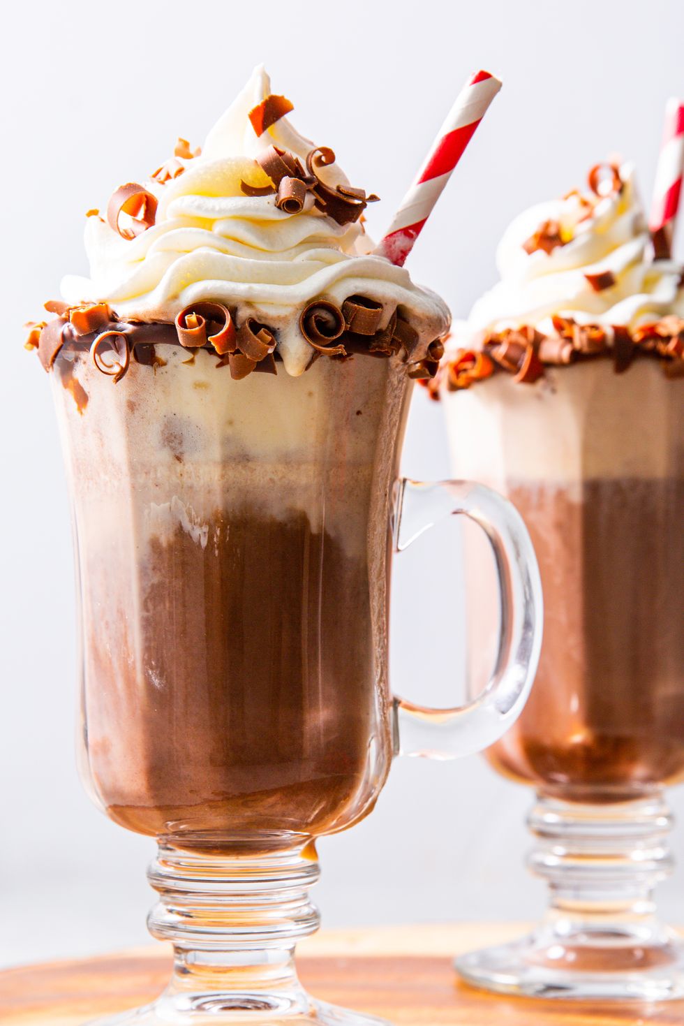 boozy hot chocolates garnished on the edge with chocolate curls and topped with whipped cream