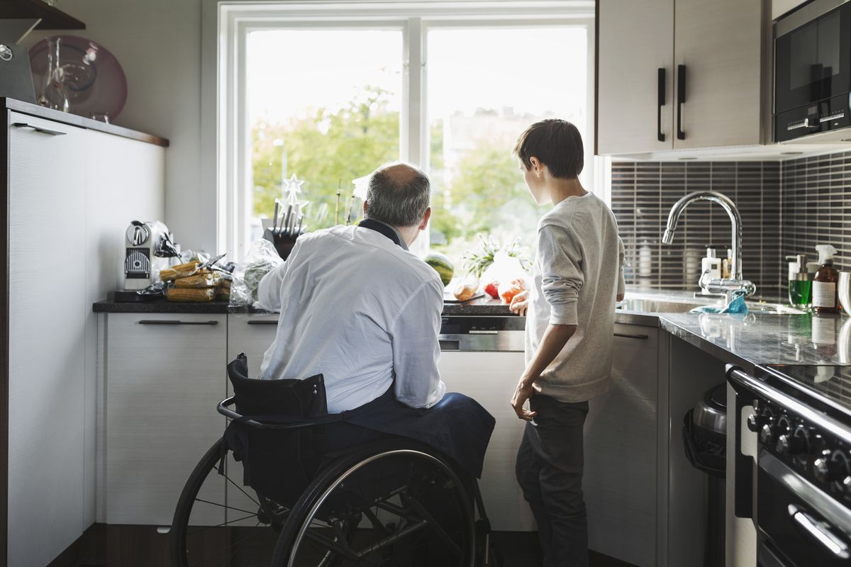 disabled father preparing food son in kitchen