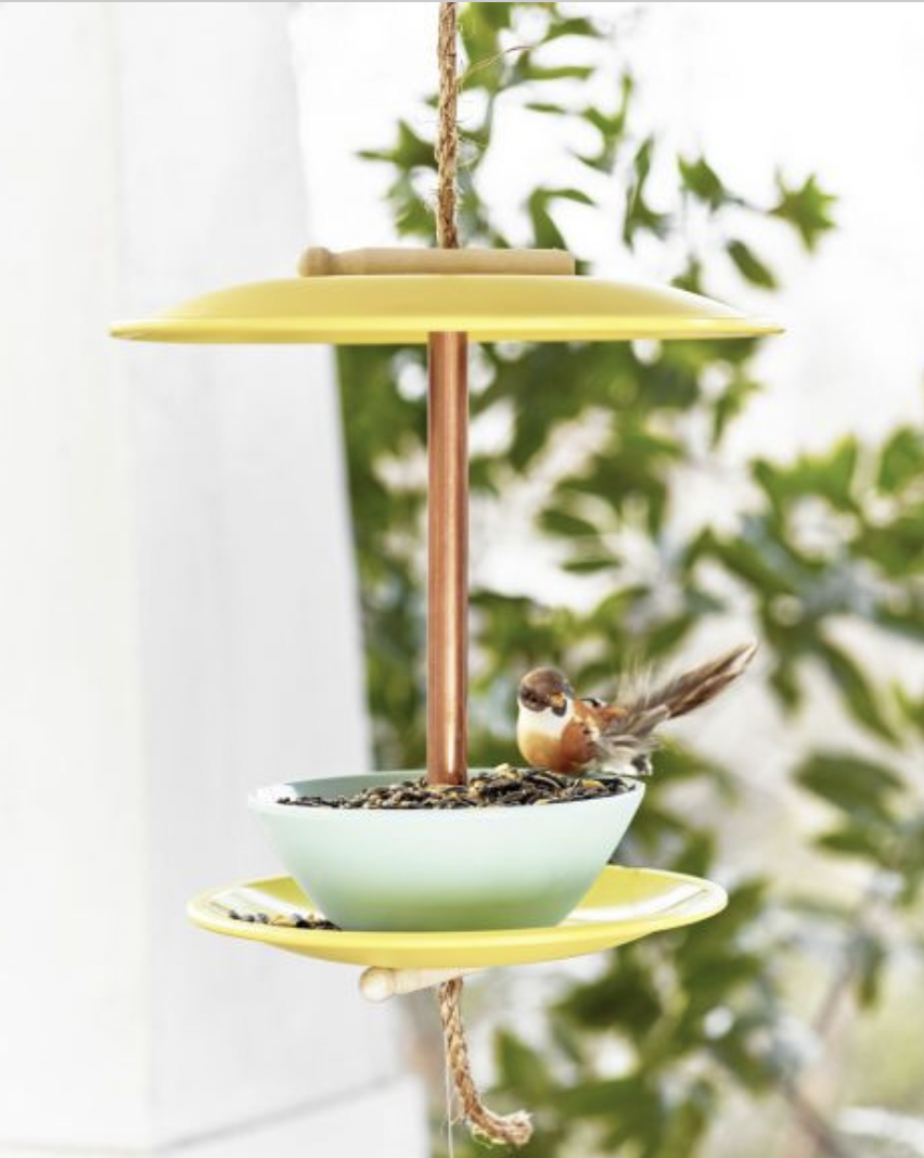 a bird feeder made from yellow and blue melamine plates and blows hung on a front porch
