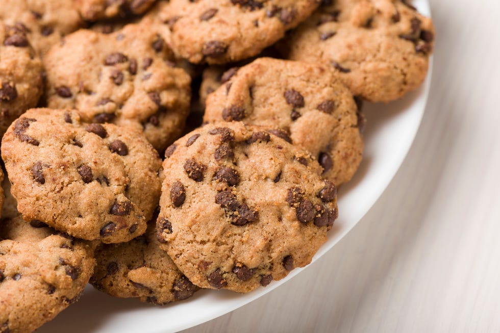 Dish of gluten-free craft biscuits with chocolate nuggets over white wooden background