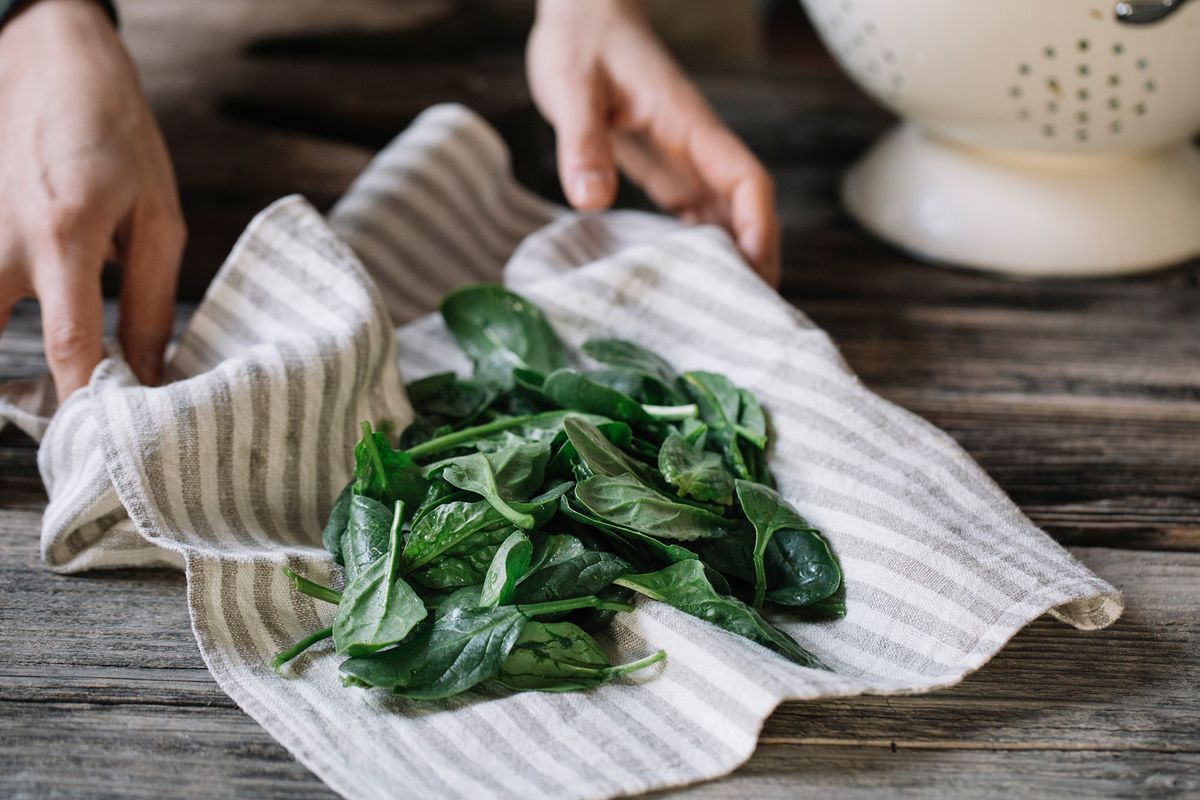 hands with dish towel and spinach