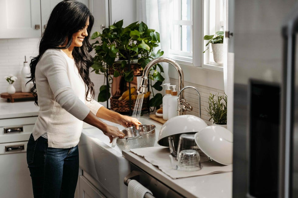 person washing dishes at a kitchen sink with a modern aesthetic