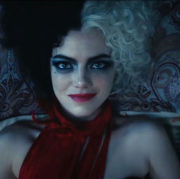 emma stone looking up at the camera from a dark bed with a smirk in disney's cruella
