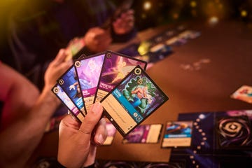 a hand holds cards from ravensburger's disney lorcana deck