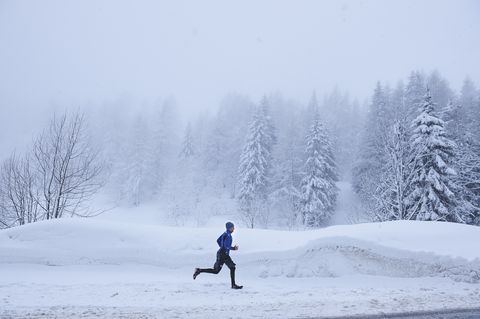 distant view of male runner running in deep snow, gstaad, switzerland