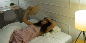 woman fanning herself while trying to sleep