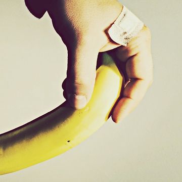 Cropped image of man holding banana against wall