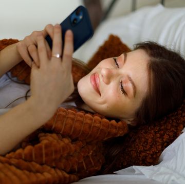 een vrouw ligt in bed en kijkt op haar telefoon