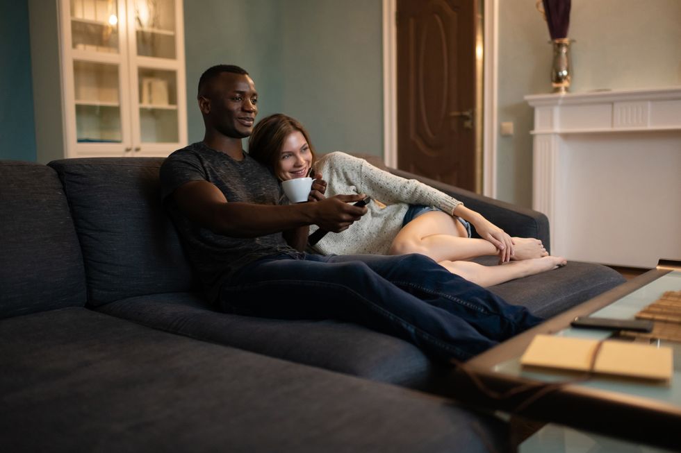 diverse couple cuddling on sofa and watching tv together