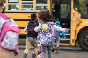 diverse group of happy children getting on school bus