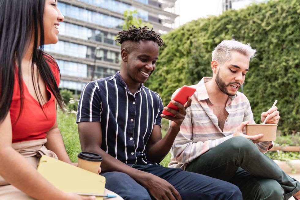 diverse people having fun eating takeaway food outdoor in the city focus on non binary man