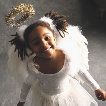 young girl wearing an angel costume with a halo, wings, and white dress