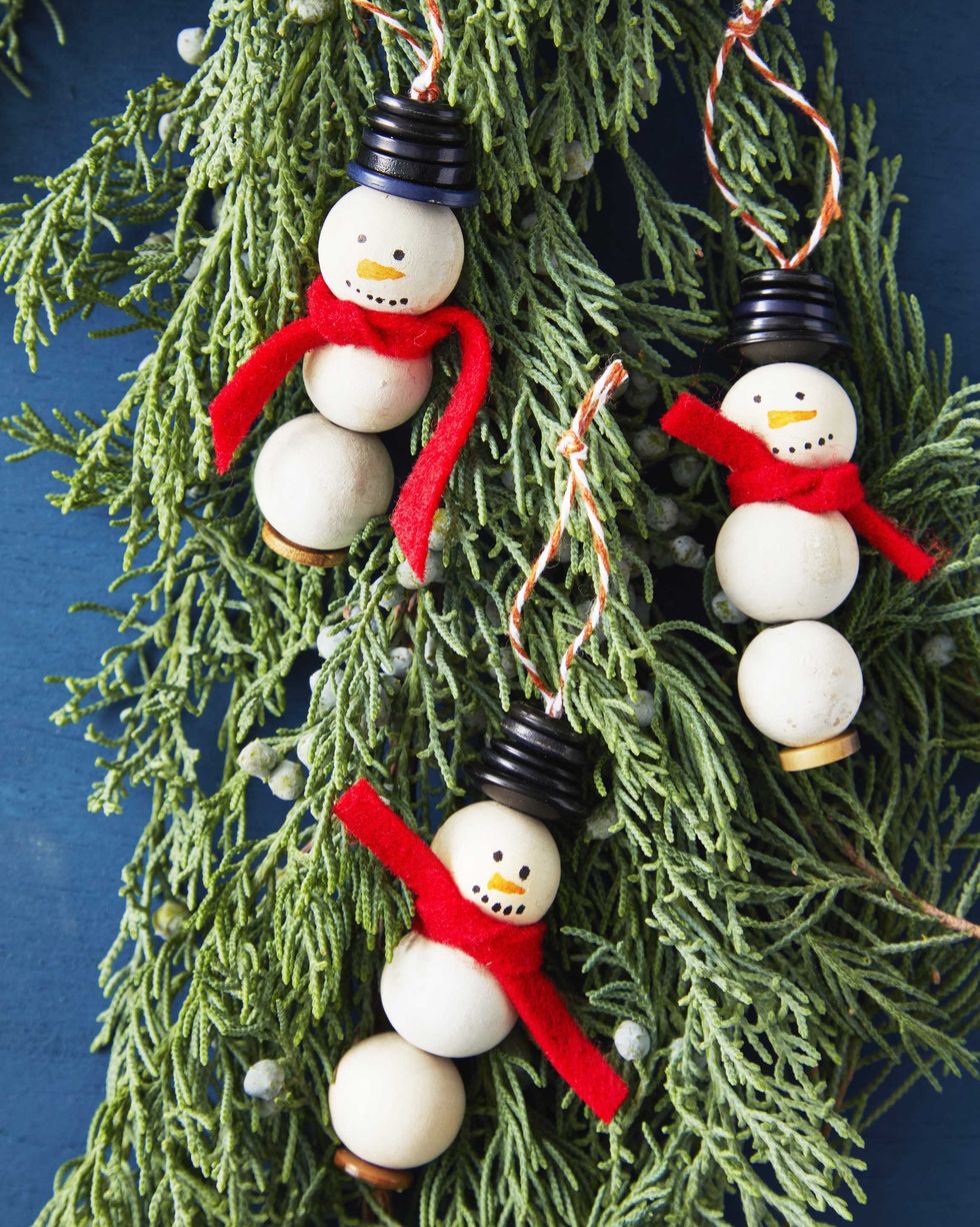 snowman oraments made from wooden craft beads with button hats and a red felt scarf resting on greenery