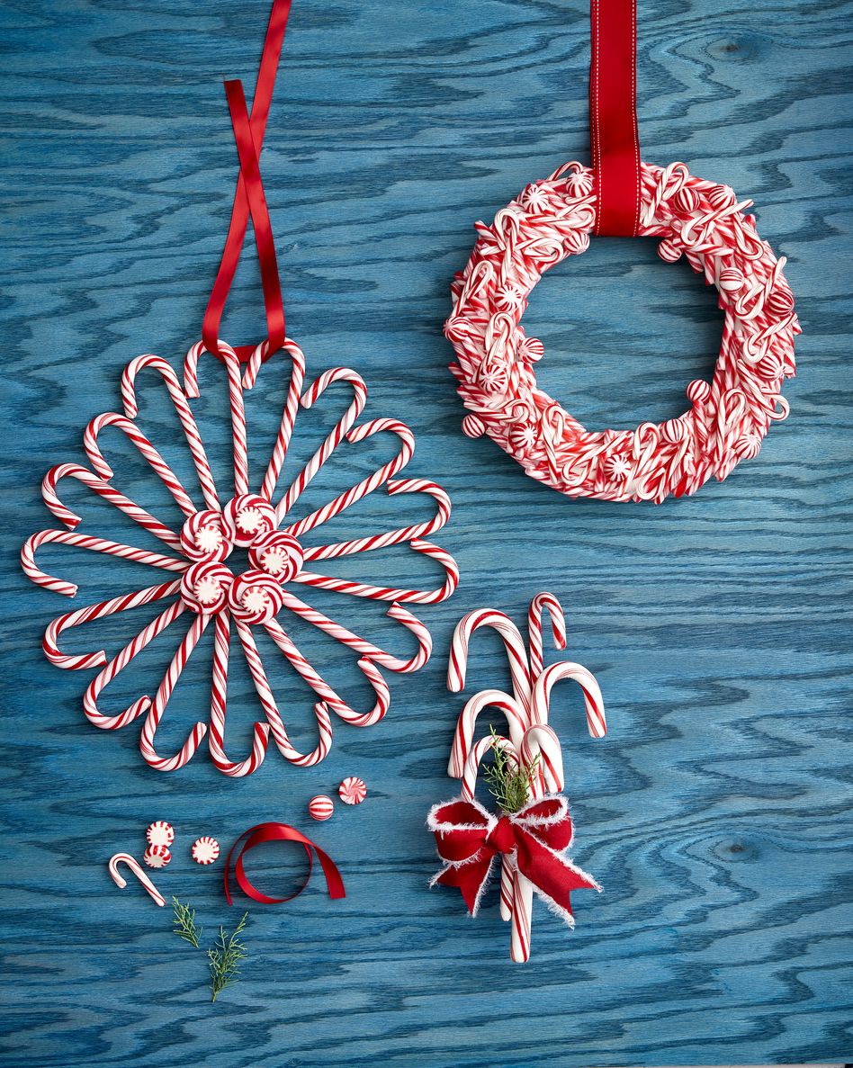 two wreaths made out of candy canes and one door swag made out of giant candy canes and tied with ribbon