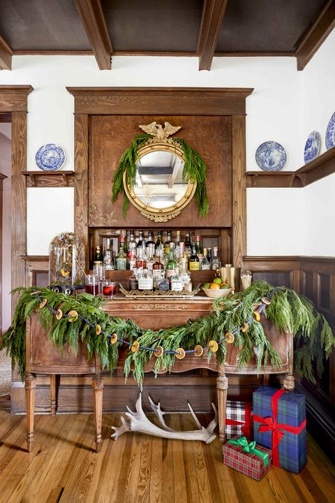 a dried citrus garland with plaid ribbon is layered on a swag of greenery that is draped on a bar