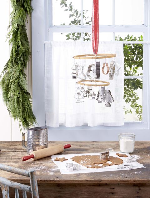 a hanging mobile made from embroidery hoops and vintage cookie cutters hung above a table where gingerbread cookies are being made