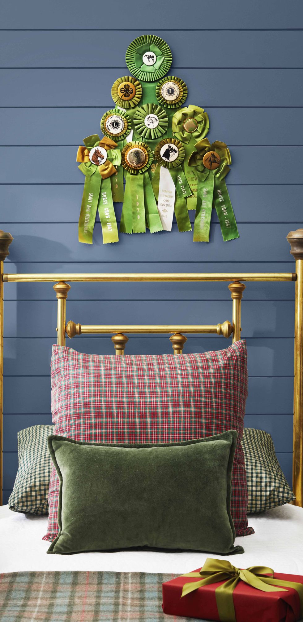 green prize ribbon hung in the shape of a christmas tree on the wall above a brass bed
