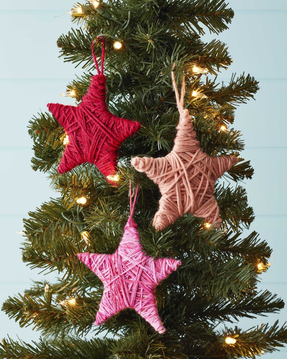 star christmas ornaments made from cardboard and yarn hung on a mini tree