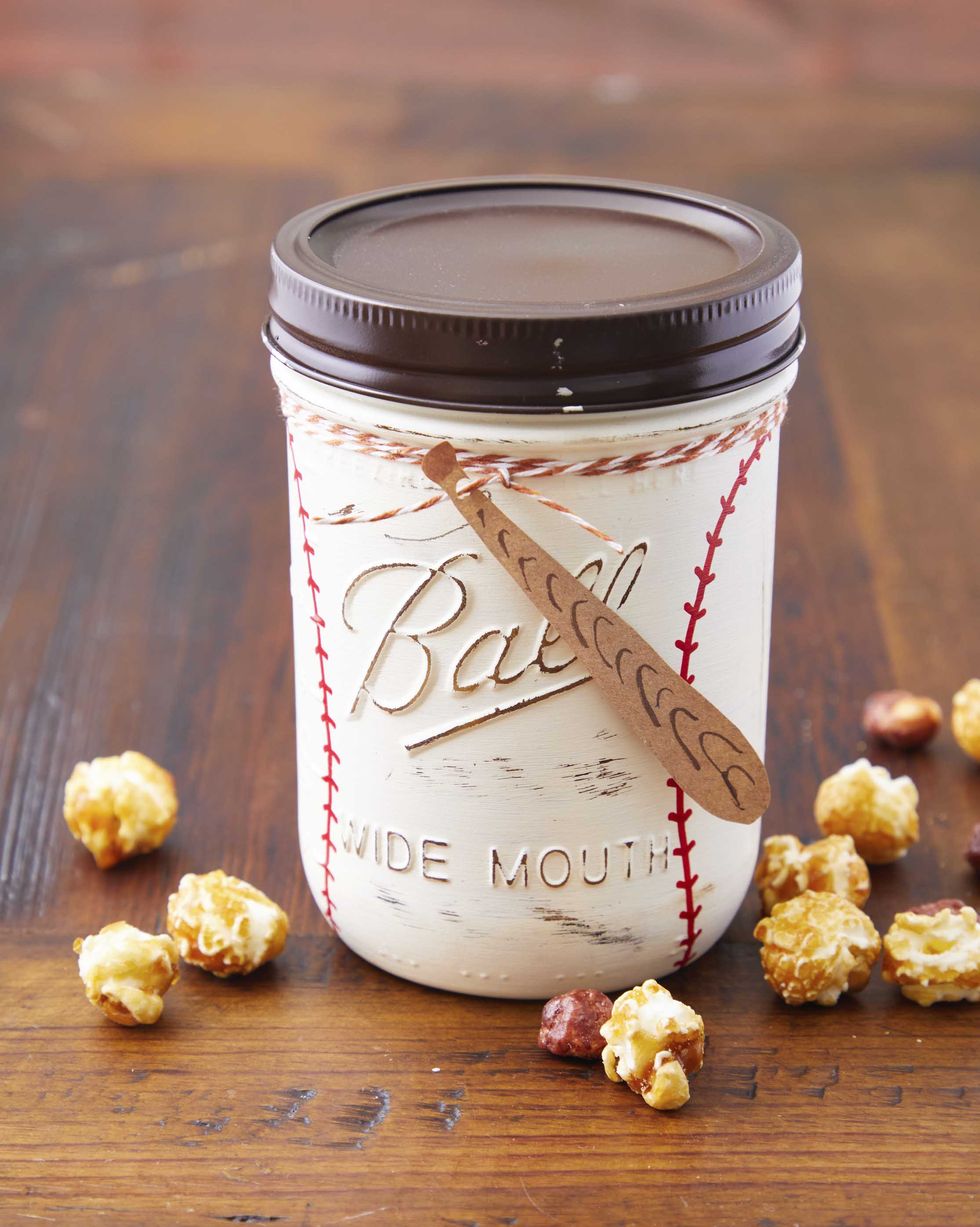 a mason jar decorated like a baseball with a paper bat tag filled with candied popcorn