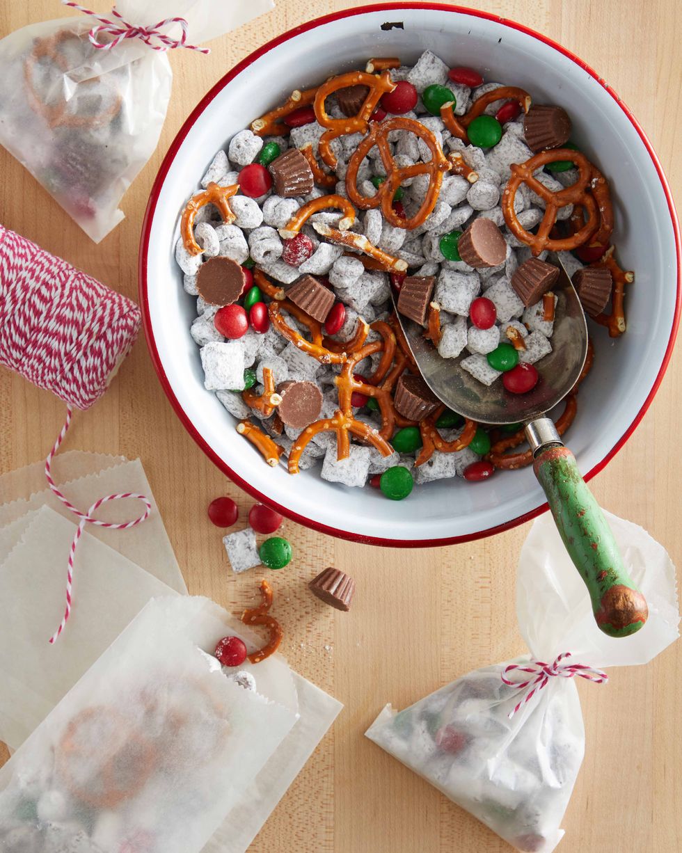A bowl is filled with sweet snack mix and a glassine bag filled with the mixture is placed on a table nearby