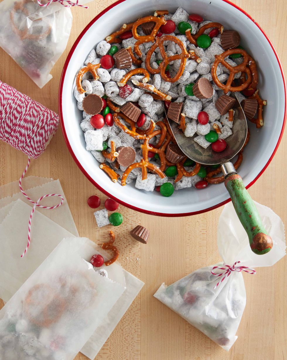 a sweet snack mix in a bowl with glassine bags filled with the mix laying on the table nearby