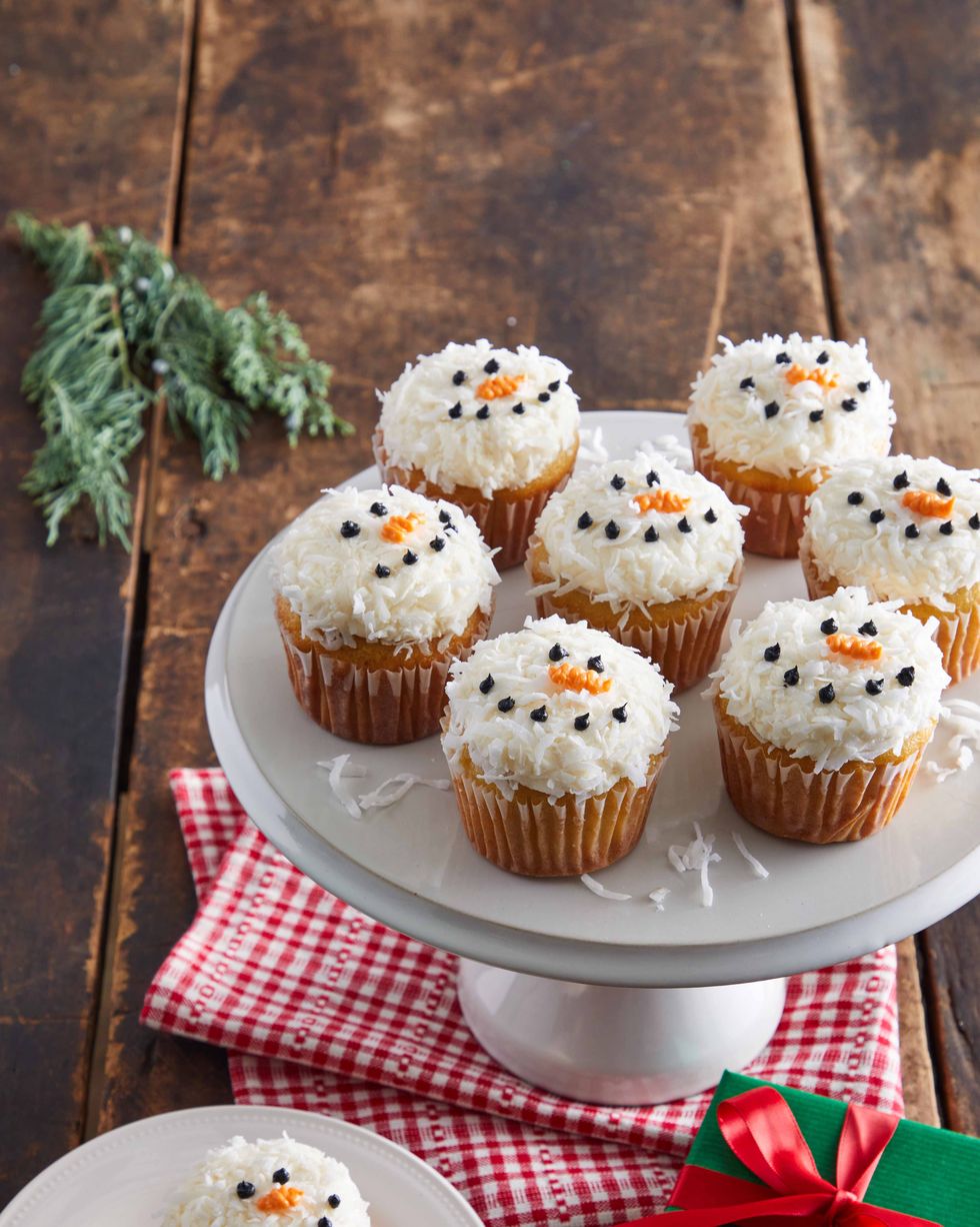 vanilla cupcakes topped with white frosting cocnut and decorated with a snowman face using icing