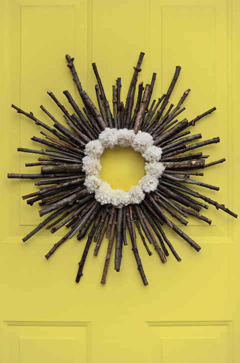 diy christmas wreath, wreath made of twigs and pom poms hanging on a yellow door