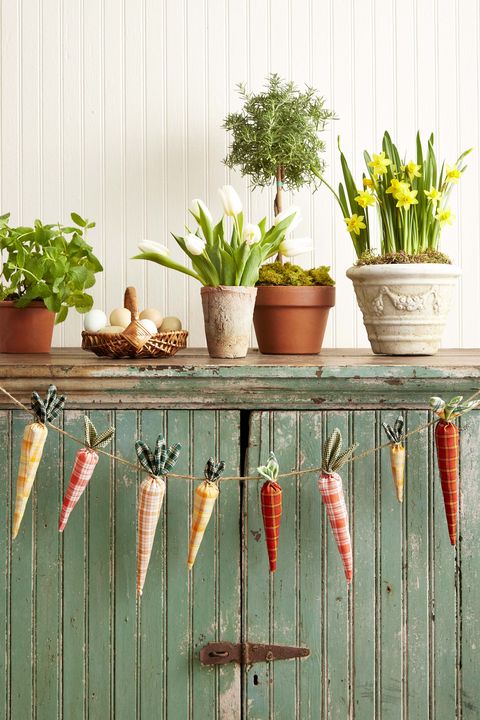 carrot garland made from fabric on a green cabinet that's topped with flowers and plants