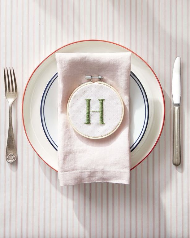 embroidered hoop with initial "h" on it set on a dinner plate