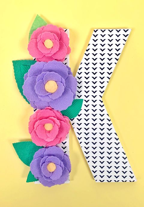 the letter k printed out with a triangle pattern, decorated with flowers, a great baby shower idea