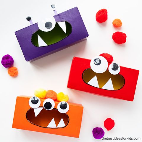 a group of tissue box monsters with googly eyes sit on a white background, with pom poms around the feed them with the project is a good housekeeping pick for best activities for kids