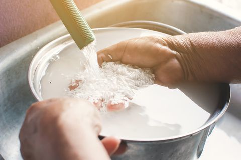 natural hair treatment person rinsing rice in a pot under the faucet