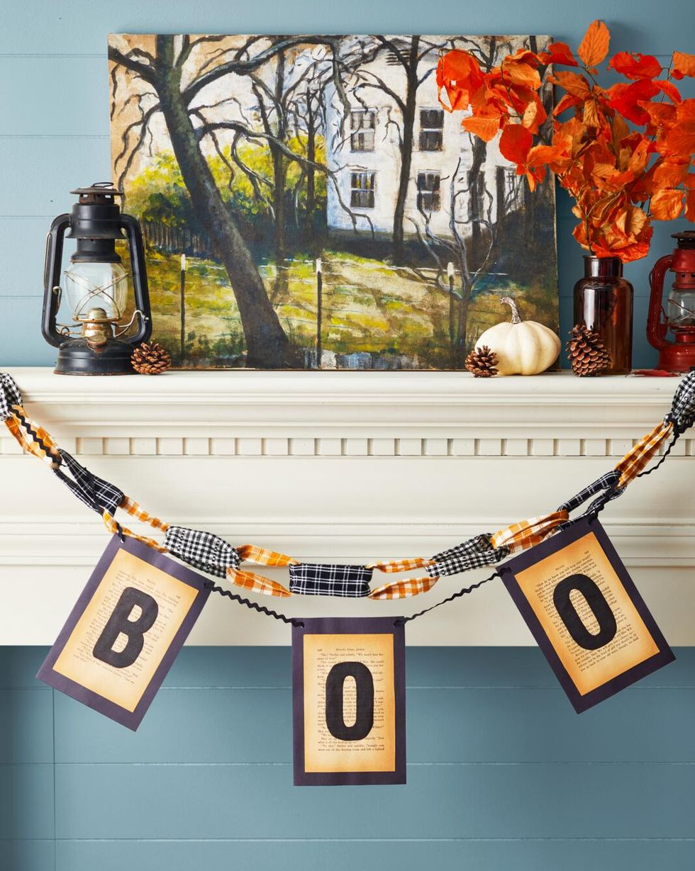 boo garland made from vintage book pages hung on a mantel