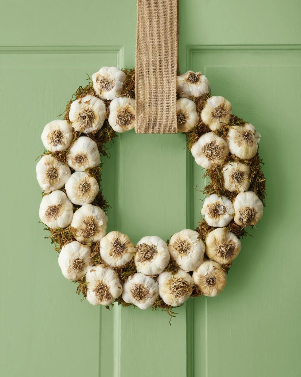 a halloween garlic and moss wreath hung on a light green door