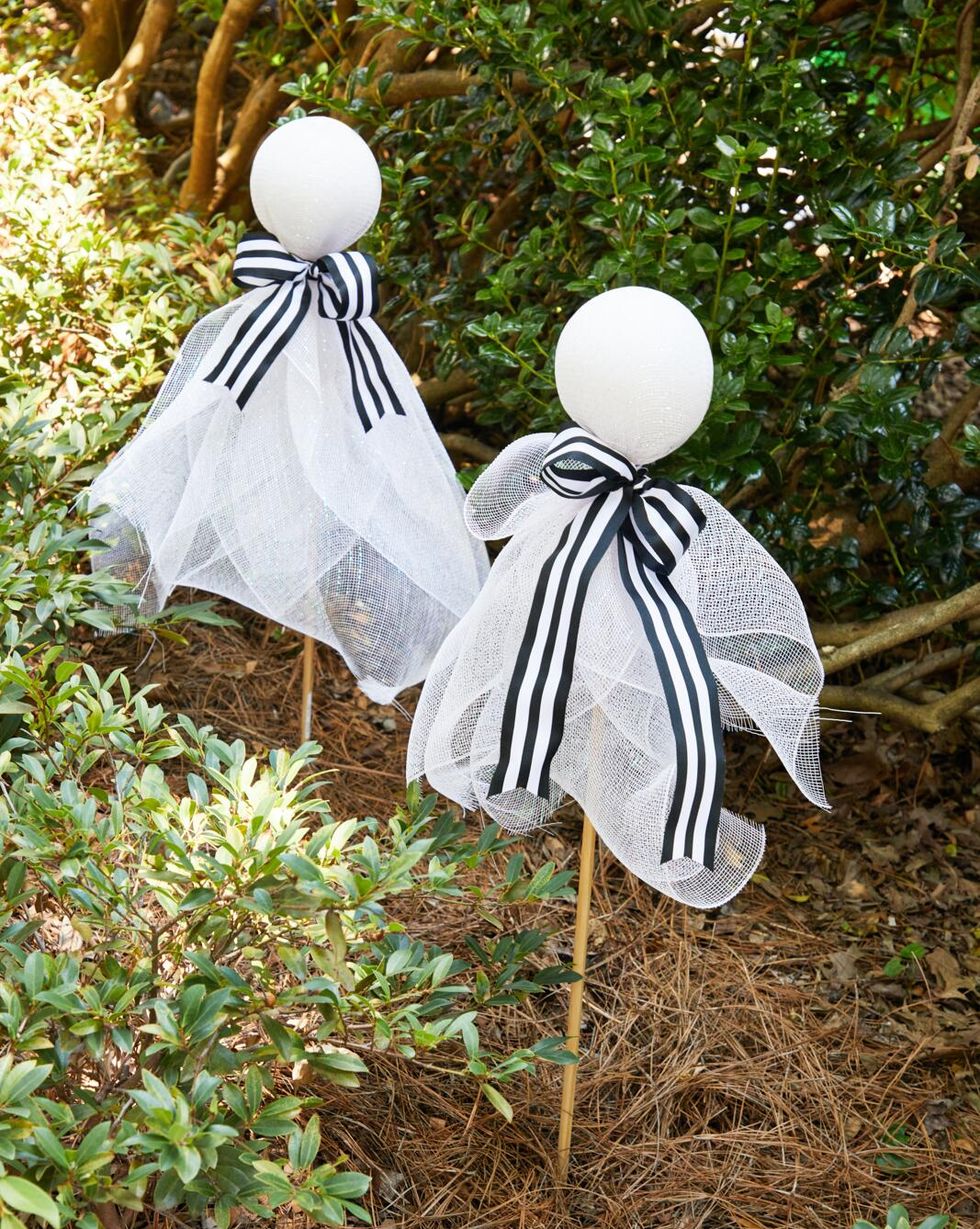 ghosts made from styrofoam balls and ribbon set in a front yard