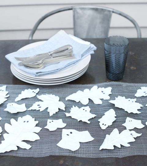 leaves painted white with two black eyes to look like ghosts displayed on table as diy halloween decorations