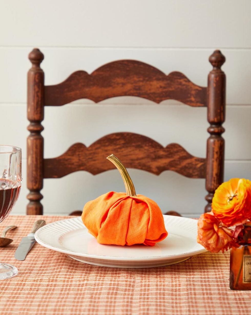 an orange napkin folded into the shape of a pumpkin set on a white plate