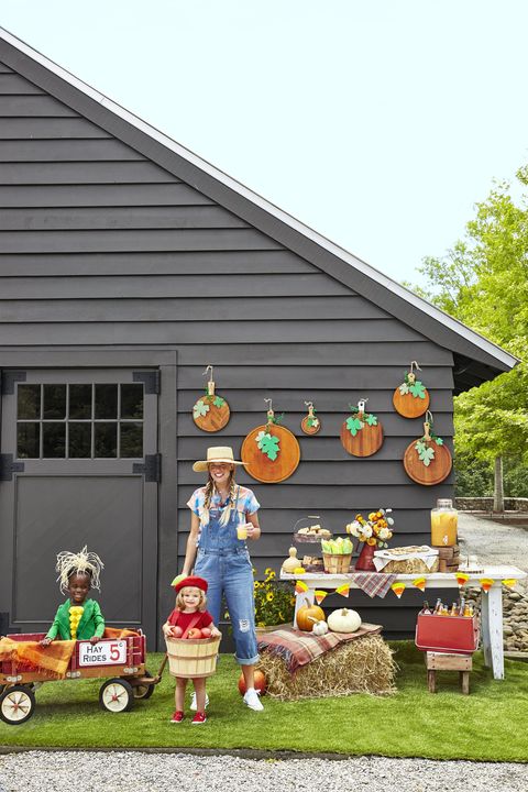 diy halloween outdoor party decorations including cutting board pumpkin wall hangings, hay bales, candy corn garland