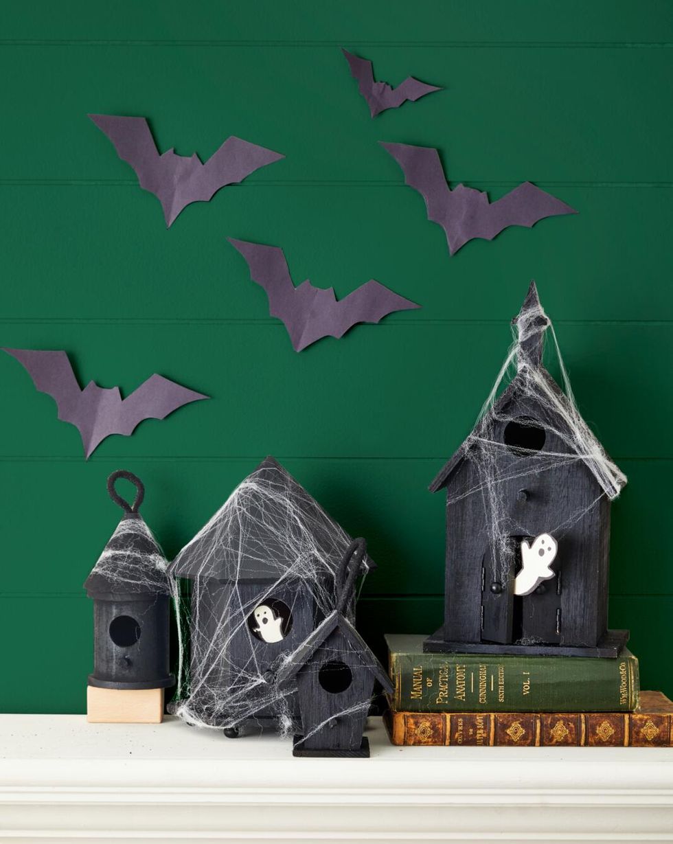 wood birdhouses painted black for halloween set on a mantel draped in faux spider webs