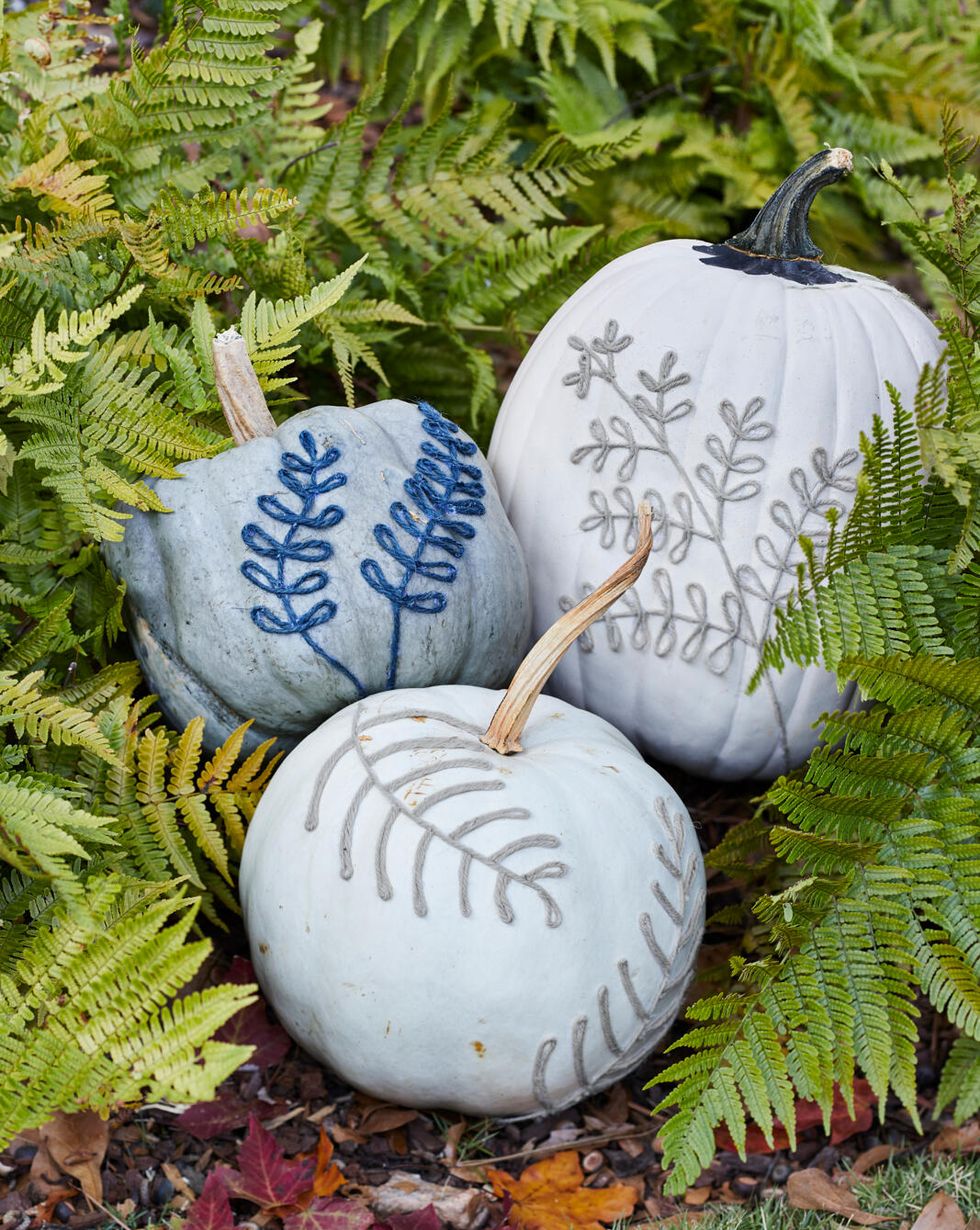 blue and white pumpkins decorated with leaf shapes made from twine