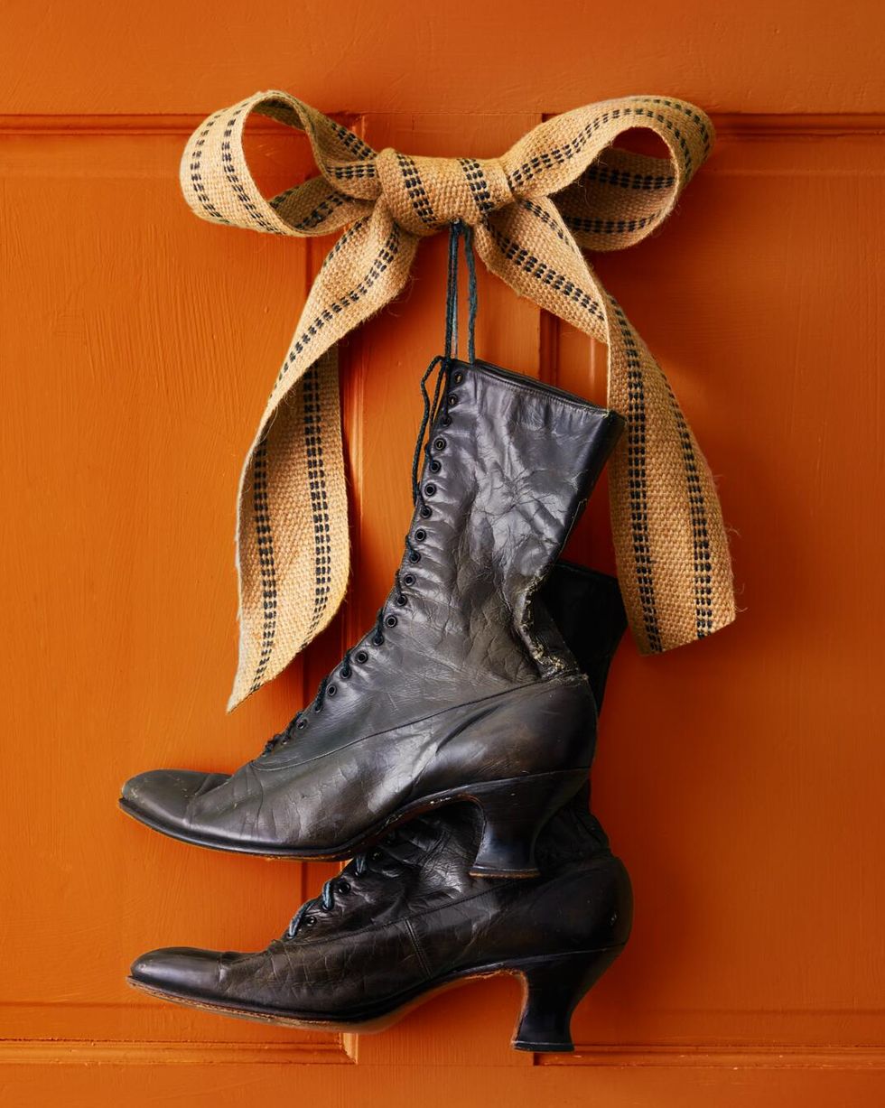 victorian sytle black boots hung on an orange fron door to mimic witches boots
