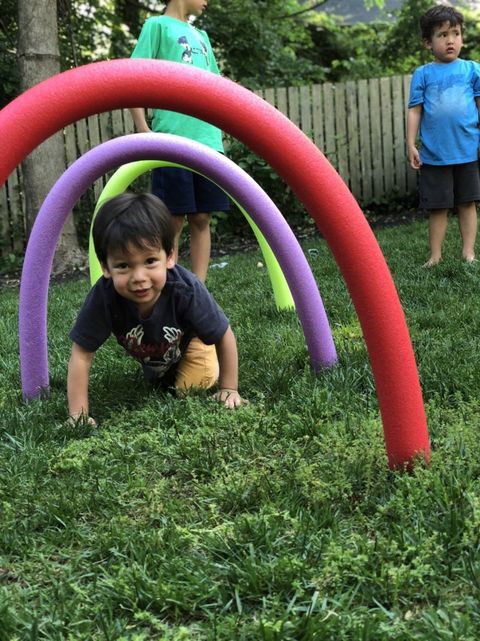 a child crawls through a pool noodle obstacle course the project is a good housekeeping pick for best activities for kids
